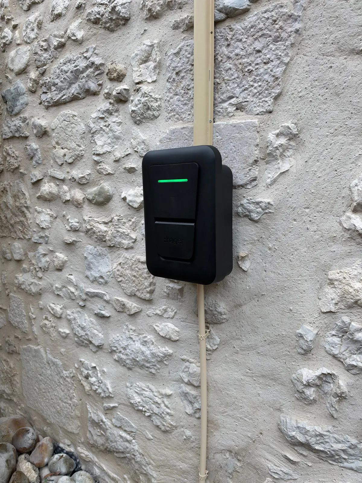 Borne Hager Witty One 11 kW triphasée vue de côté sur un mur en pierre, avec le profilé oméga ton pierre qui masque le câble, Ceyzérieu (01)