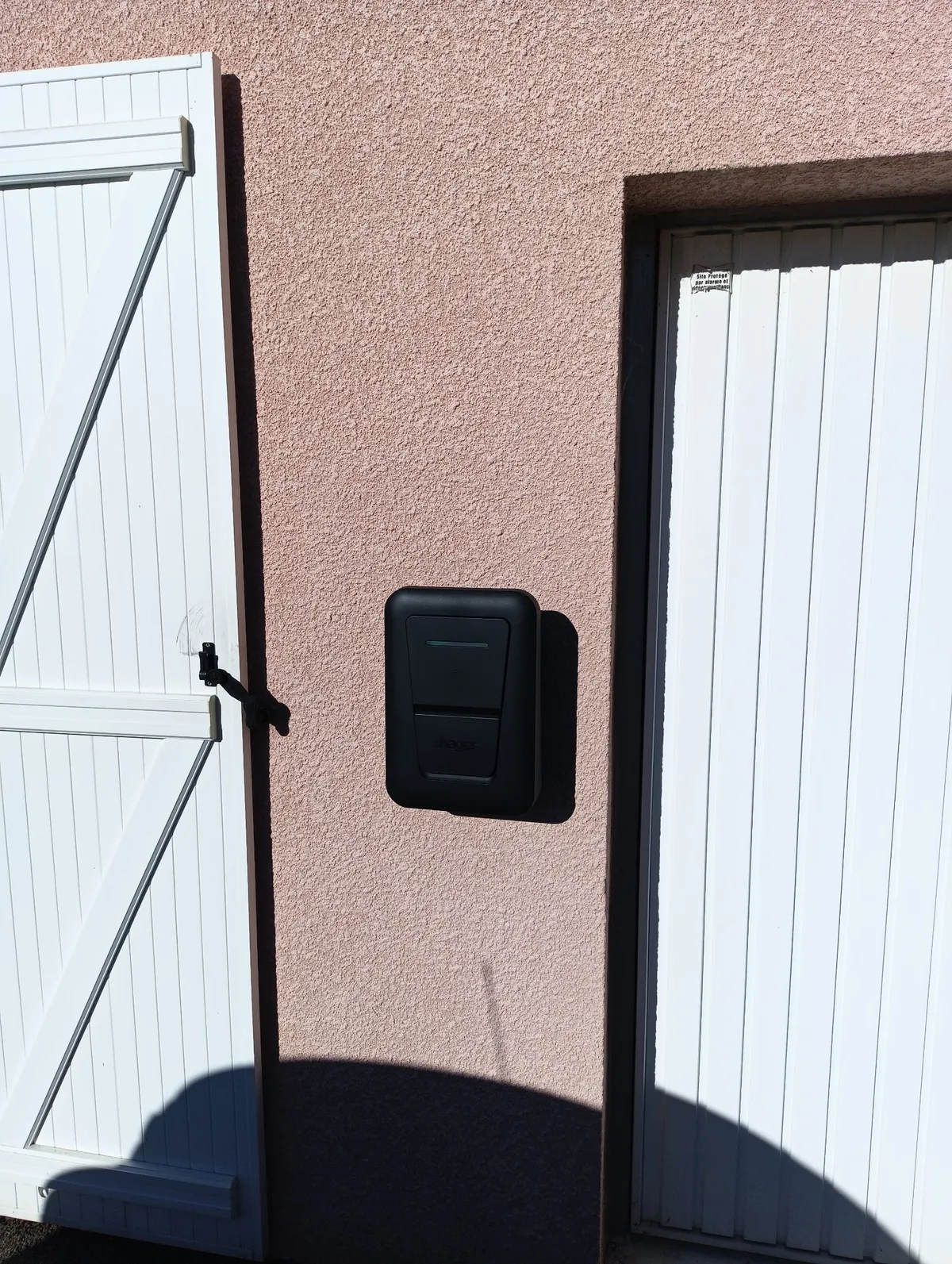 Borne de recharge Hager Witty one XVR107STI posée en façade enduite entre deux portes blanches, Artemare, Ain, GDM second œuvre